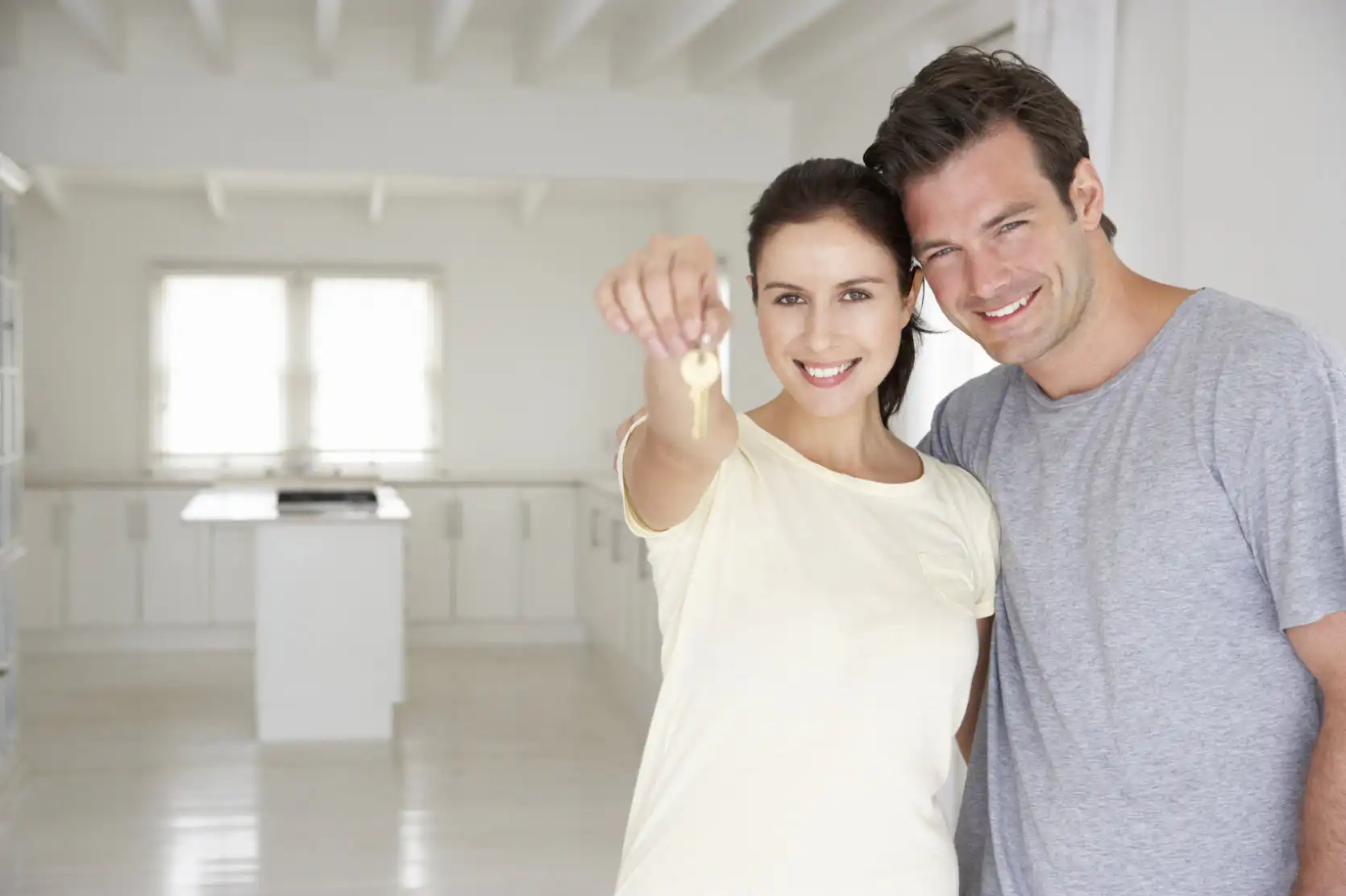 Couple holding keys inside their new home after buying their first house