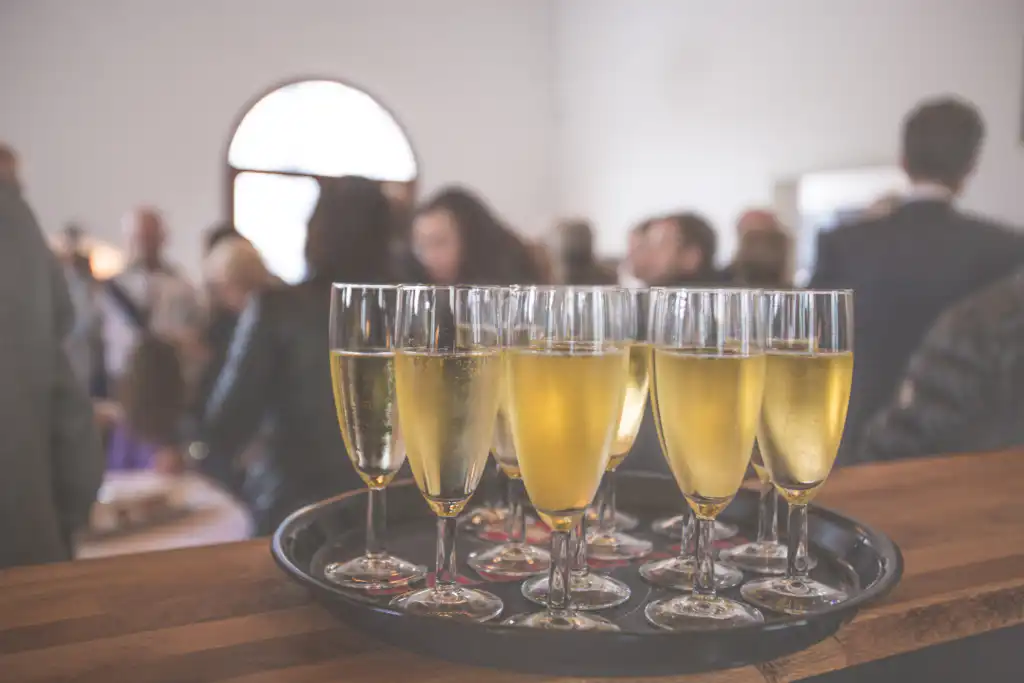 Champagne glasses in foreground with people networking at a broker open house event