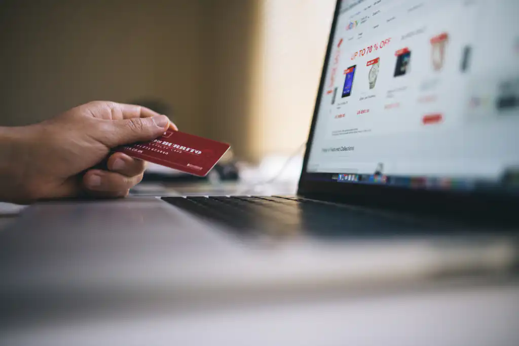 Man holding a credit card while using a laptop to check his credit score