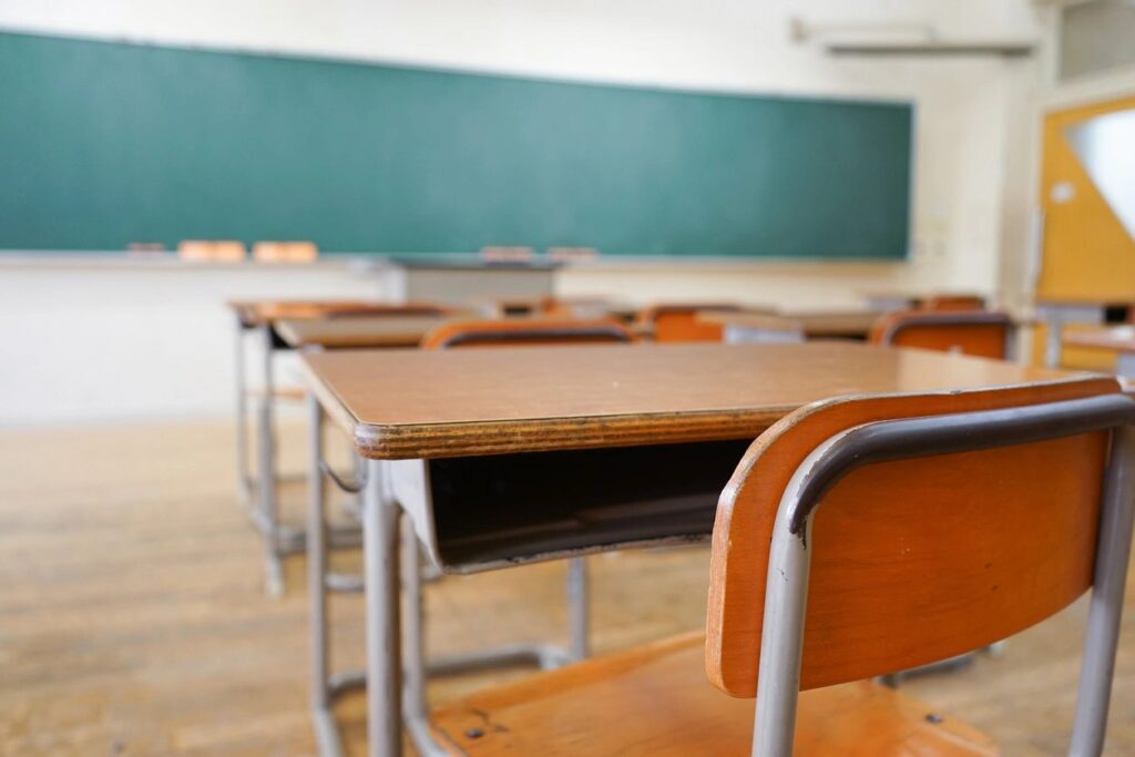 Empty classroom with desks and a green chalkboard